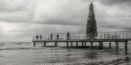 People by sea against sky