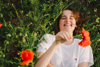 Happy cheerful teen girl with pronounced face dancing in outdoors in a field with red poppies.