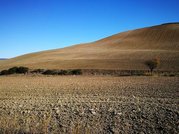 Scenic view of desert against clear blue sky