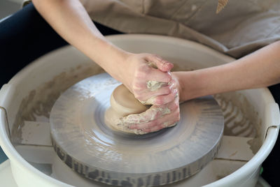 Midsection of woman making pot on pottery wheel