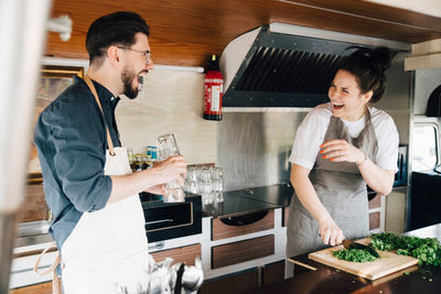 Male and female entrepreneurs laughing while standing in food truck