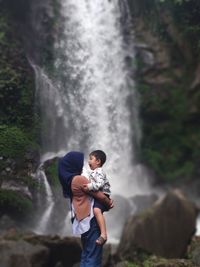 Rear view of woman standing against waterfall