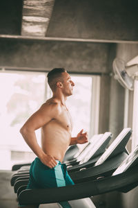 Shirtless man exercising on treadmill