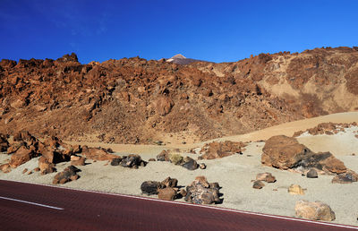 Road by rock formations against blue sky at teide national park