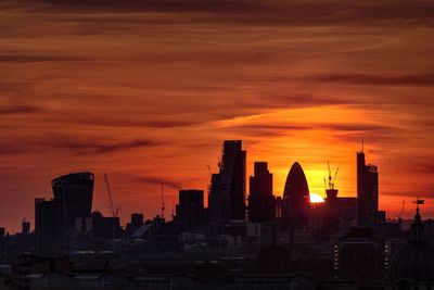 Modern cityscape against sky during sunset