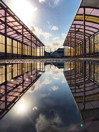 Reflection of bridge in swimming pool against sky