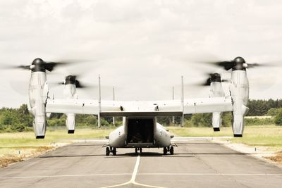 Airplane at airport runway against sky