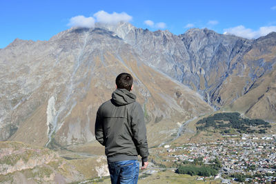 Rear view of man on rock in mountains against sky
