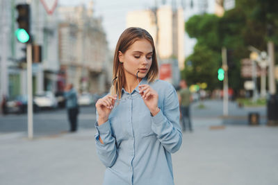 Portrait of young woman standing in city