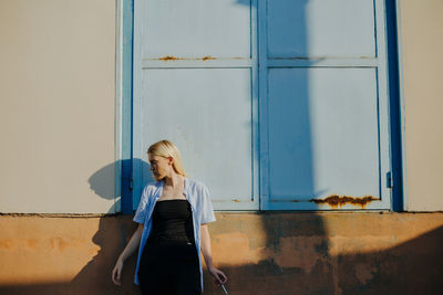 Full length of woman standing against wall