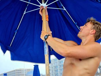 Shirtless man holding umbrella