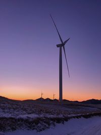 Wind turbines on field against sky during sunset