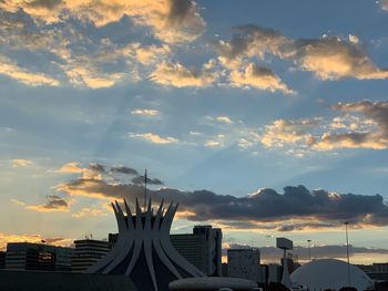 Silhouette buildings against cloudy sky during sunset