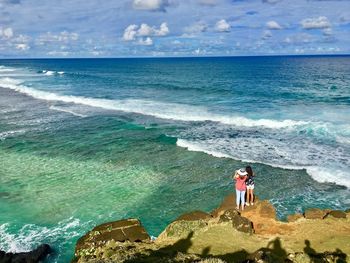 Friends standing at beach against sky