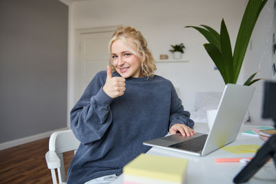 Young woman using mobile phone while sitting at home