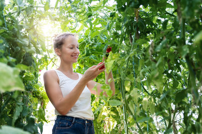 Portrait of young woman standing amidst plants