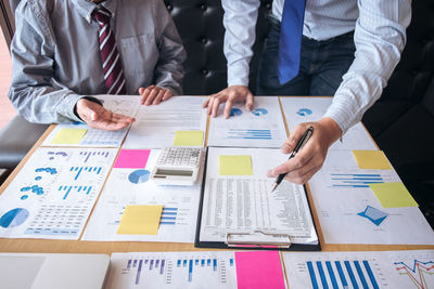 Midsection of colleagues doing paperwork at desk in office