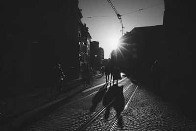 People walking on railroad track against sky