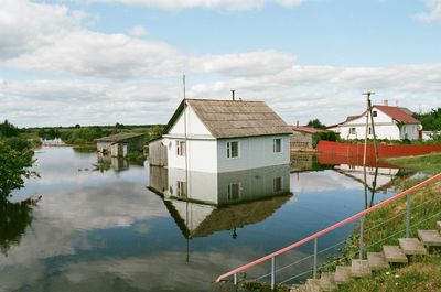 Houses by lake against sky