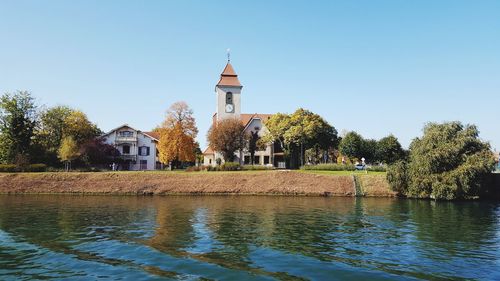 Built structure by river against clear sky