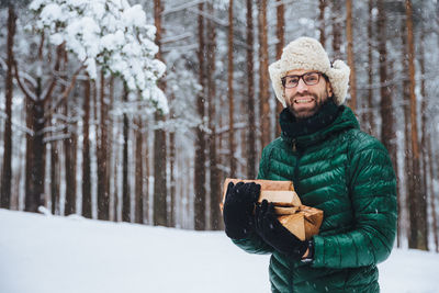 Man wearing hat standing against snow covered trees during winter