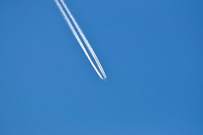 Low angle view of contrail at blue sky