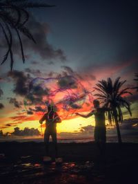 Silhouette man standing on beach against sky during sunset