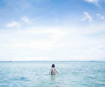 Woman in sea against sky