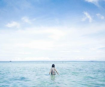 Woman in sea against sky