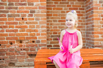 Portrait of young woman standing against brick wall