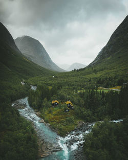 Scenic view of waterfall by mountains against sky