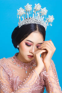 Portrait of asian woman in beautiful makeup wearing pink wedding dress, isolated on blue background.