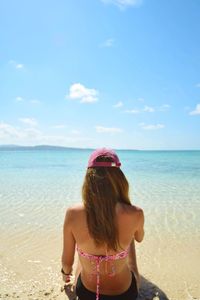 Rear view of woman on beach against sky