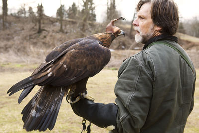 Caretaker looking away while bird perching on hand