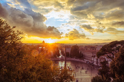 Cityscape against cloudy sky during sunset