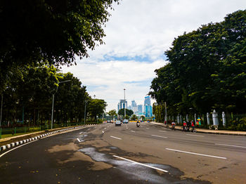 Vehicles on road along plants and trees in city