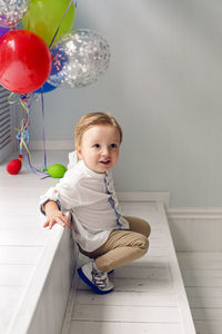 Portrait of a child boy two years old sitting on a wooden floor with balls and number two