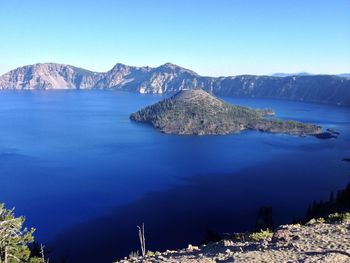 Scenic view of sea and mountains against clear blue sky