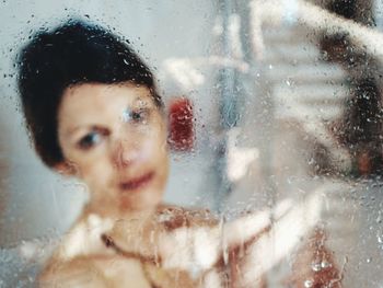 Close-up portrait of woman seen through wet glass