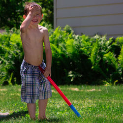 Full length of shirtless boy standing in yard