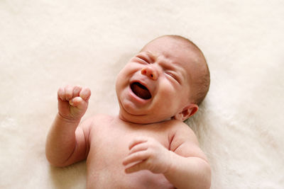 Baby girl crying while lying on bed