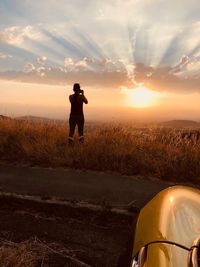 Man standing on field against sky during sunset