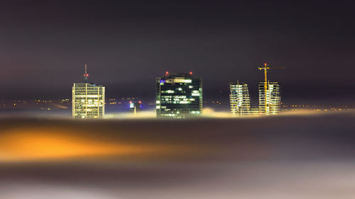 Illuminated buildings against sky at night