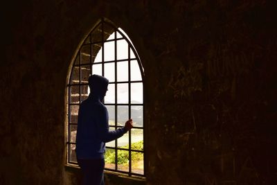 Side view of man standing by window in building