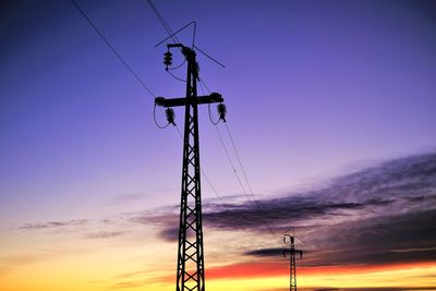 Low angle view of electricity pylon against sky during sunset