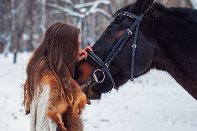 Close-up of woman with horse on snow