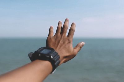 Cropped image of hand against sea