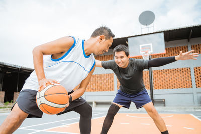 Friends playing basketball at court