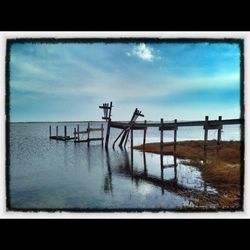 Pier on sea against cloudy sky