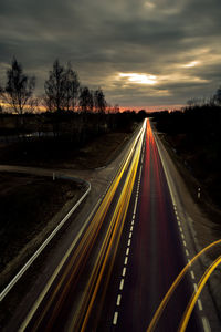 Light trails on highway against sky at sunset